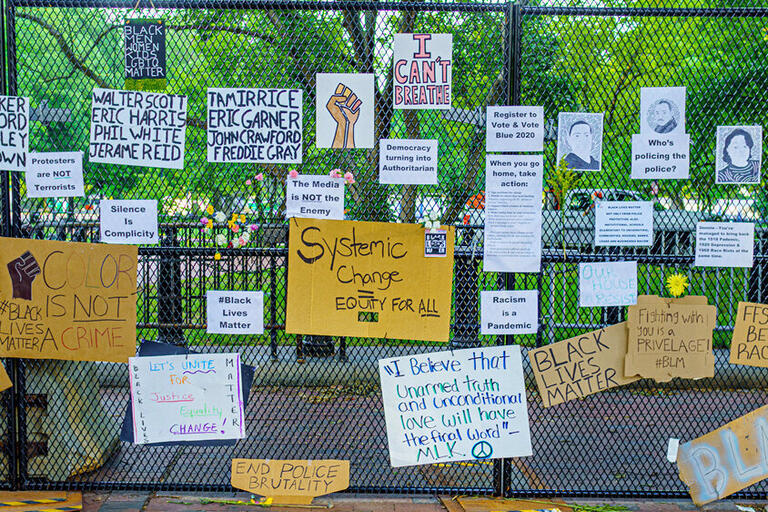 Picket signs from Washington DC protest posted on a fence that express hopes for racial and social justice 
