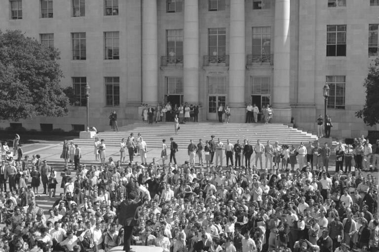 A crowd in Sproul Plaza surround Mario Savio who is on top of a police car.