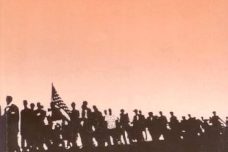Silhouettes of people marching together against an orange background