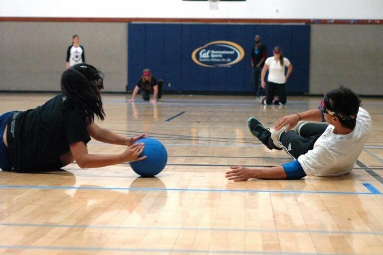 several players on the floor of a gym playing goal ball