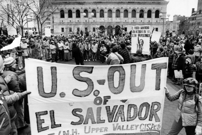 Demonstrators protesting against U.S. involvement in El Salvador holding a sign that says "US Out of El Salvador"