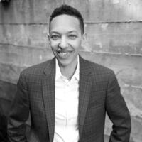 Photo of AC and Music Instructor T. Carlis Roberts smiling in formal suit attire